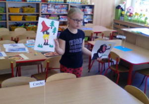 Dziewczynka prezentuje obrazki bajek czeskich- Rumcajsa i Krecika.